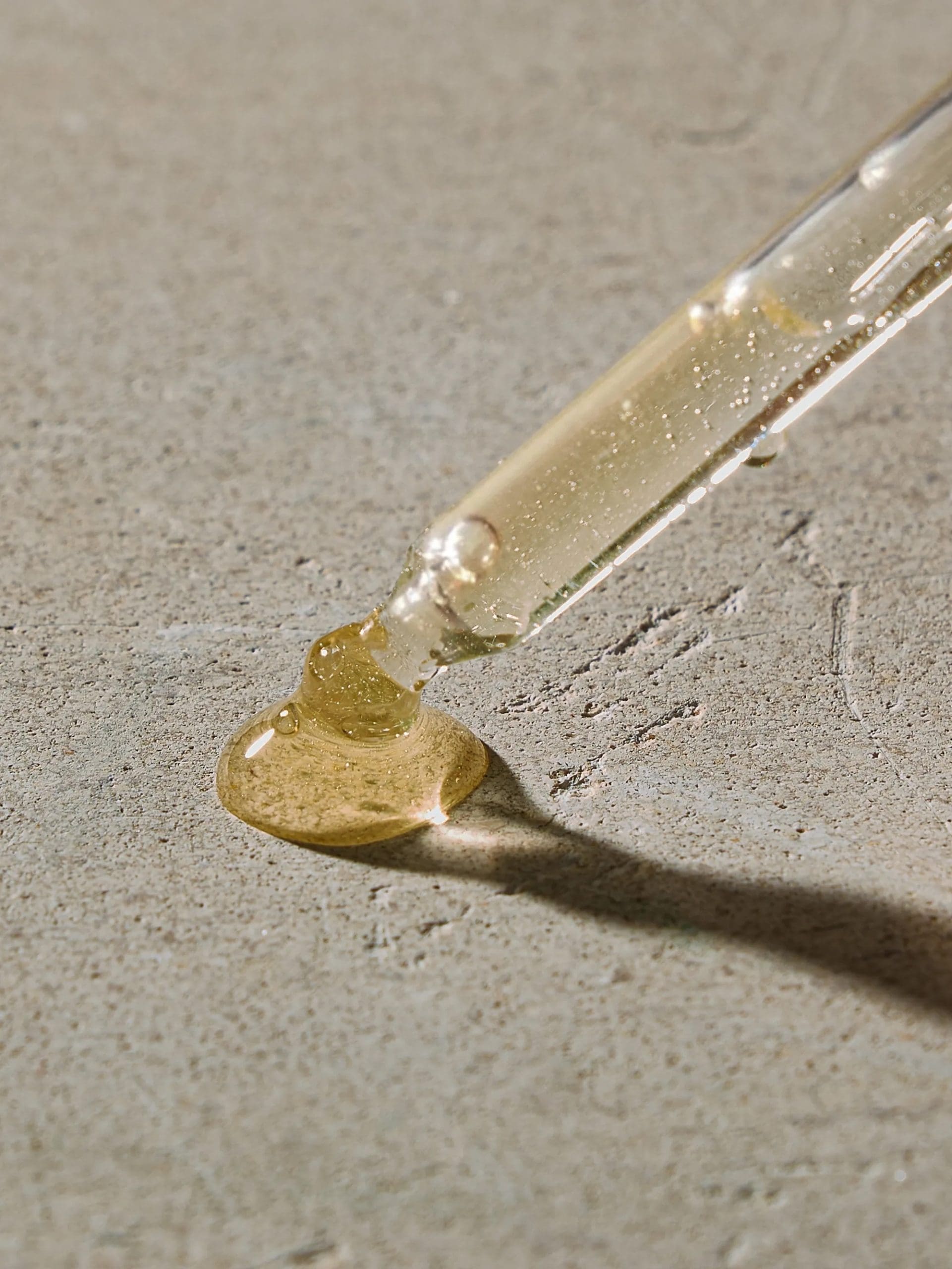 A drop of clear serum falling from a dropper