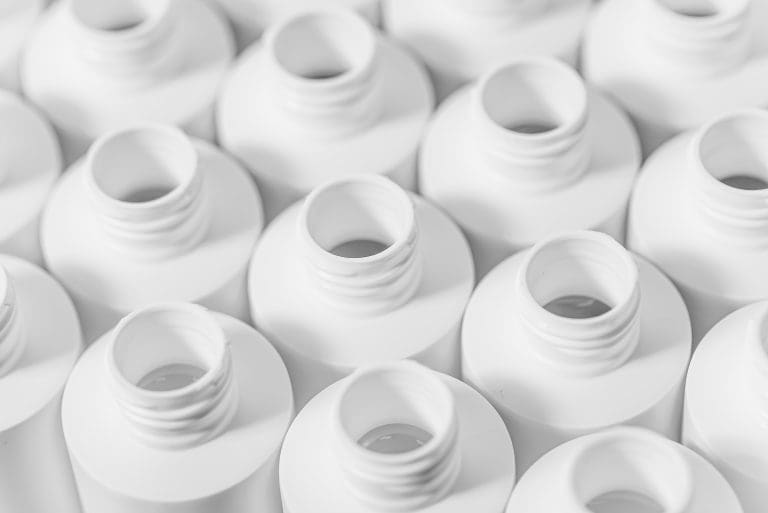 Rows of empty white plastic bottles without caps, seen from above
